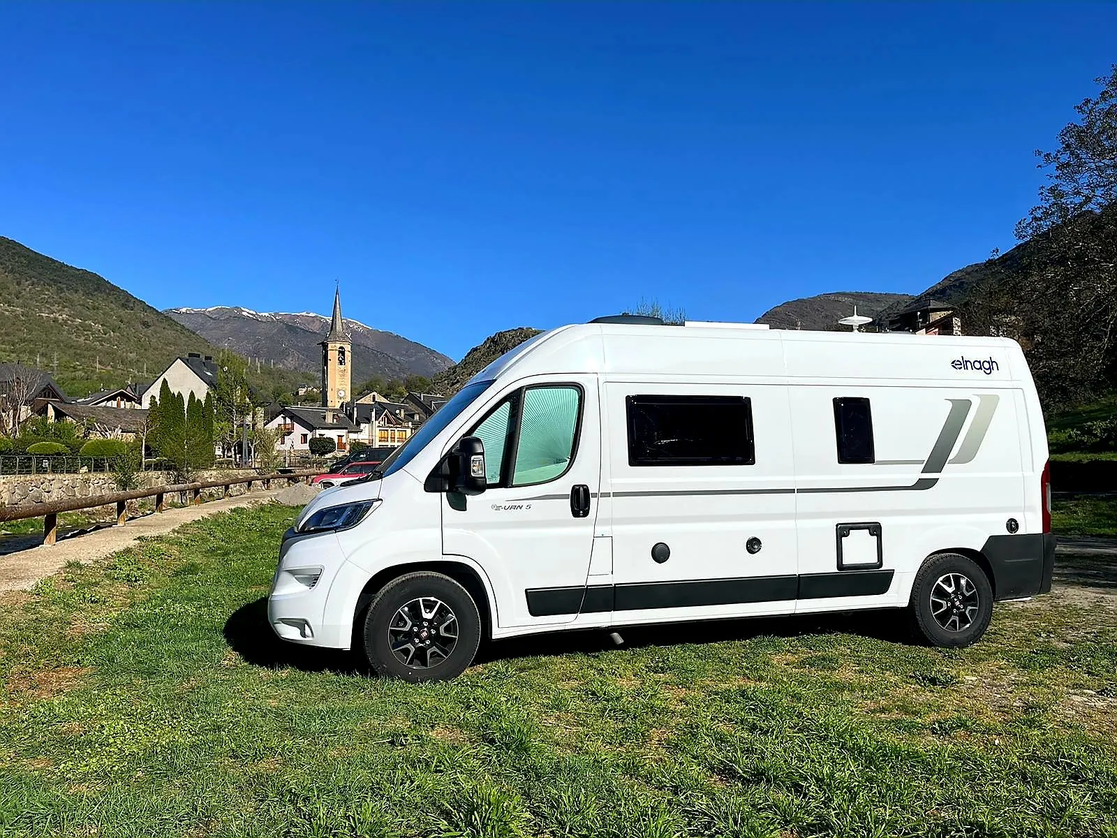 Elnagh E-Van 5 aparcada sobre l'herba a l'entrada d'un poble de muntanya